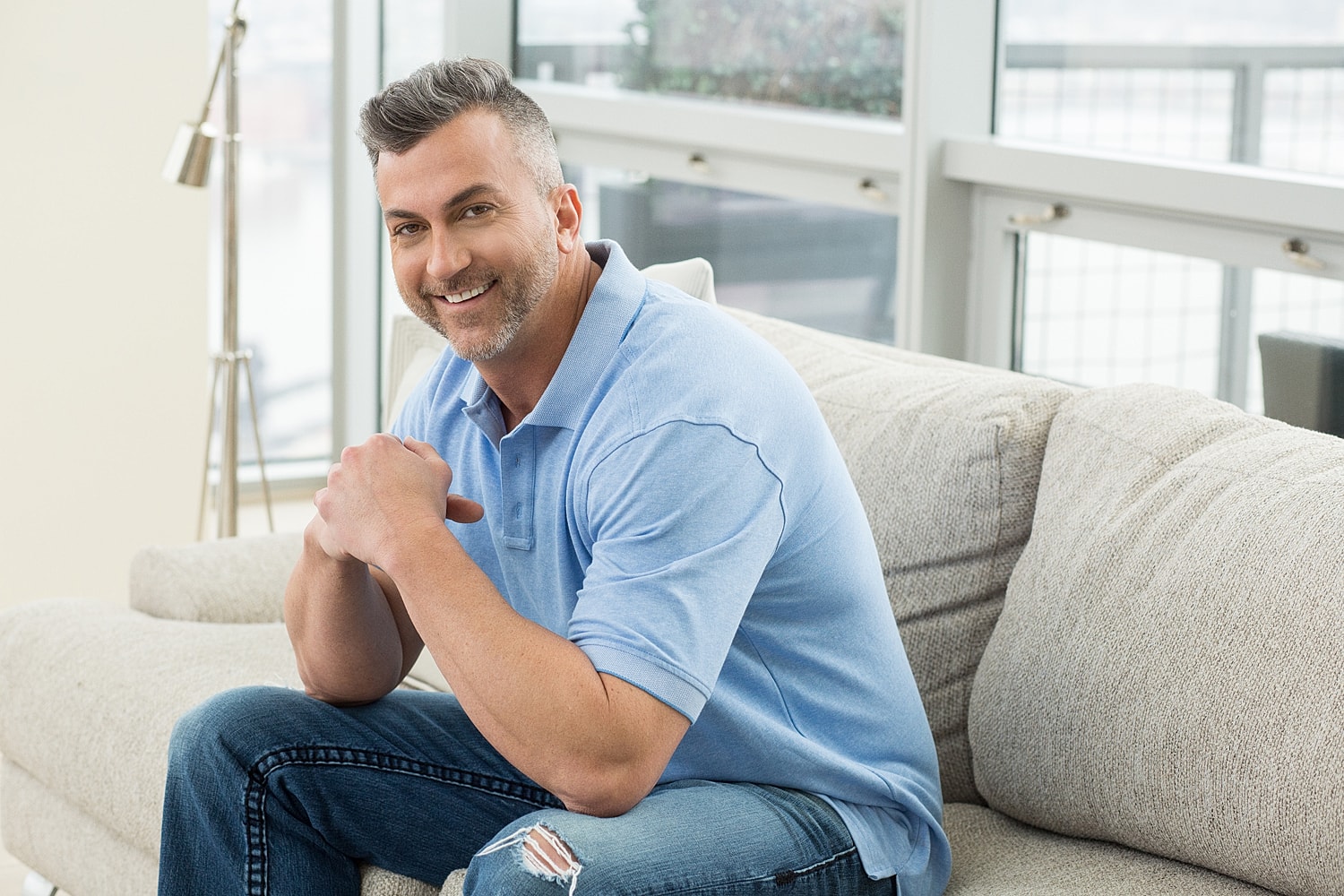 Smiling man sitting comfortably on a couch.