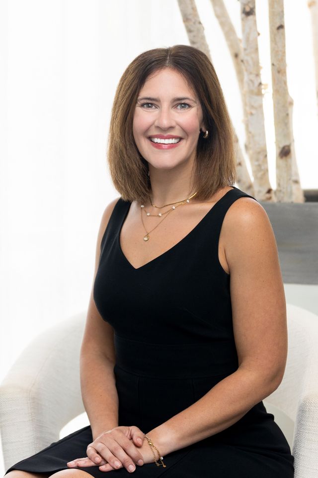 Professional woman smiling in a white blazer.