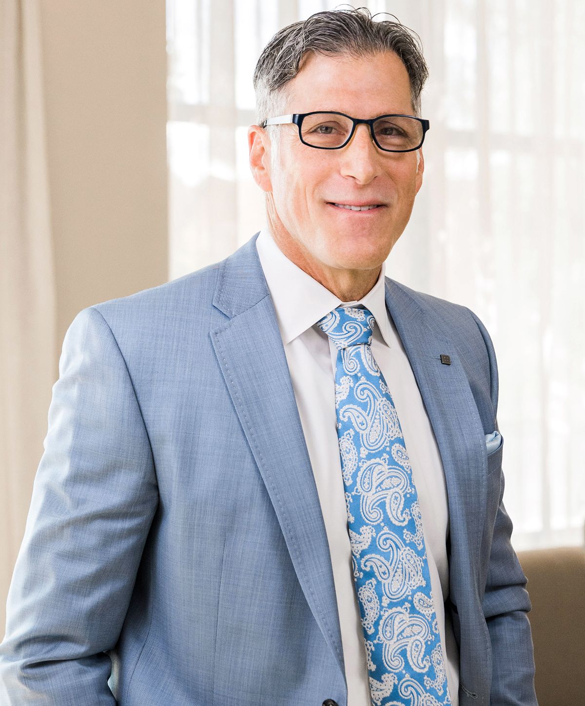 Man in business suit smiling indoors.
