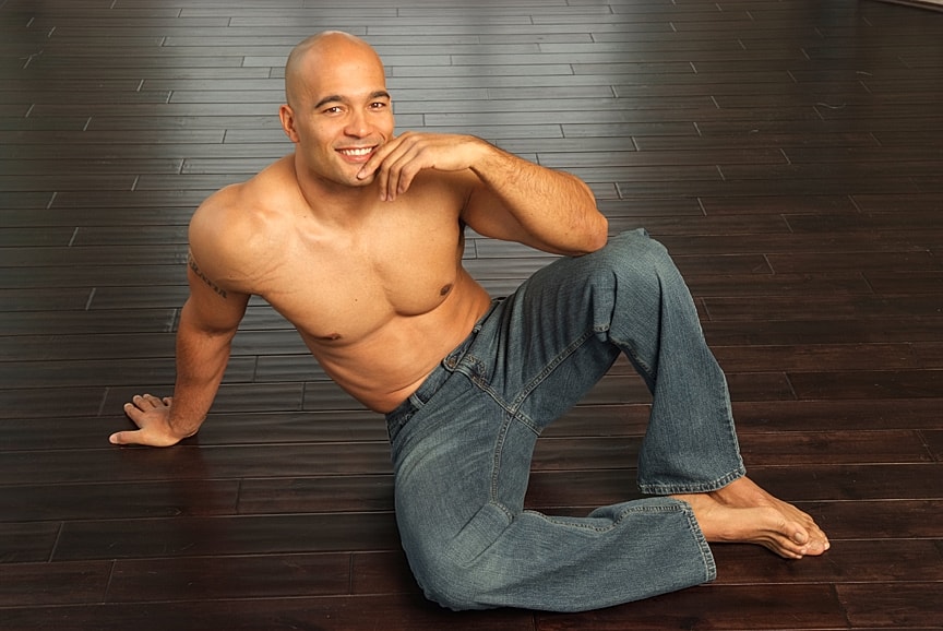 Man sitting on floor, smiling, wearing jeans.