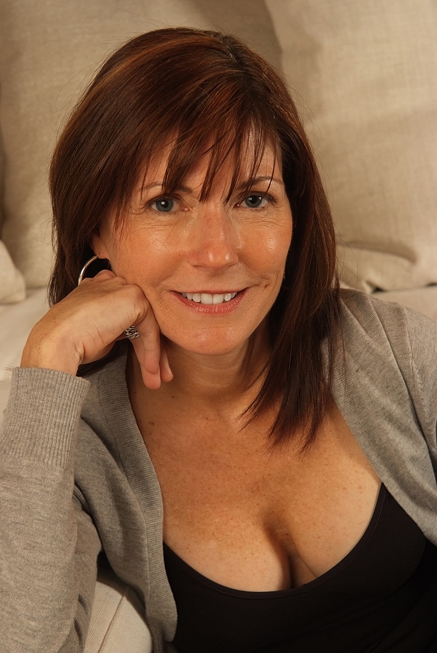 Smiling woman with brown hair in cozy setting.