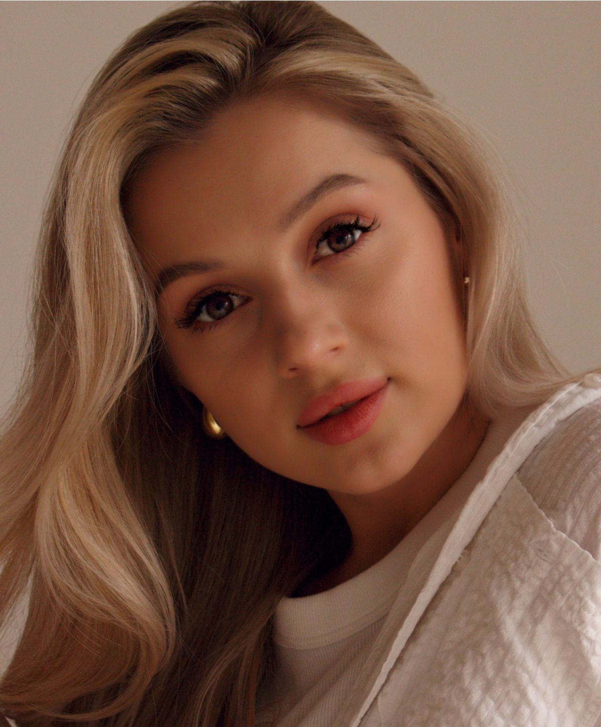 Young woman with long blonde hair and makeup.