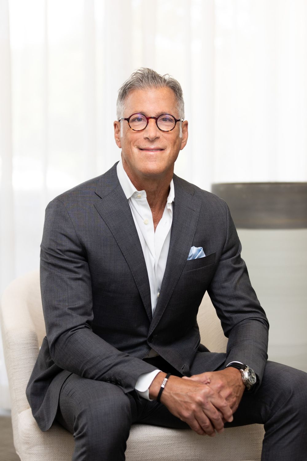 Man in a light blue suit, smiling confidently.