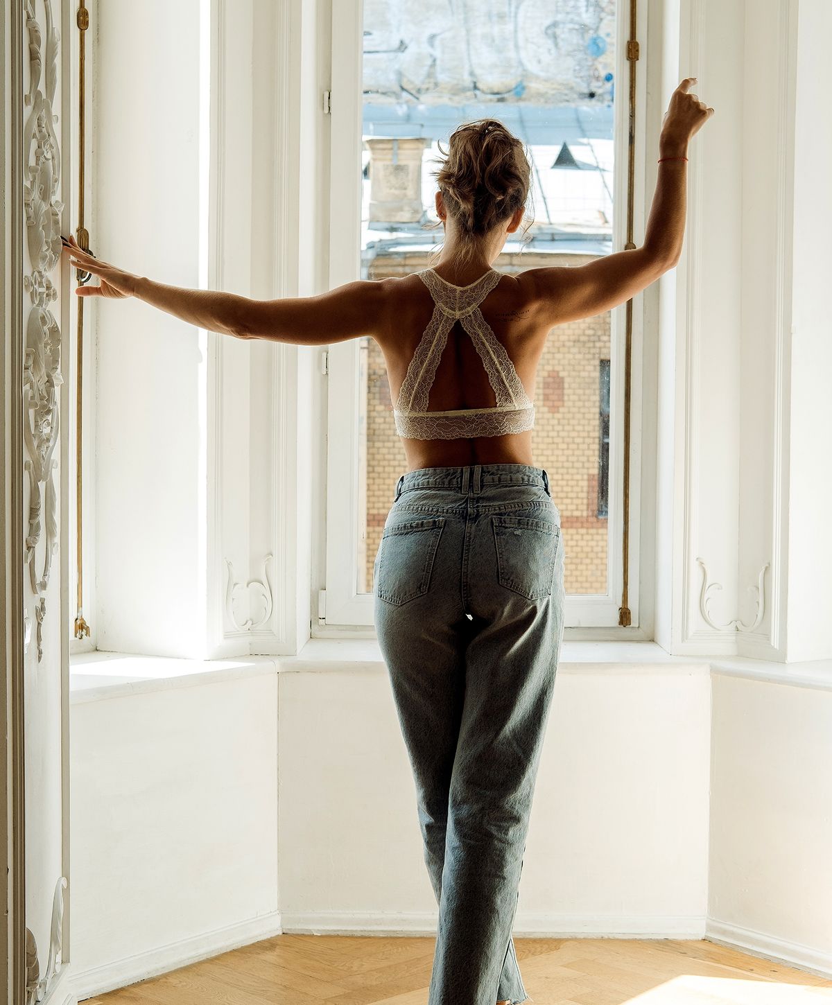Person in lace top standing by window.