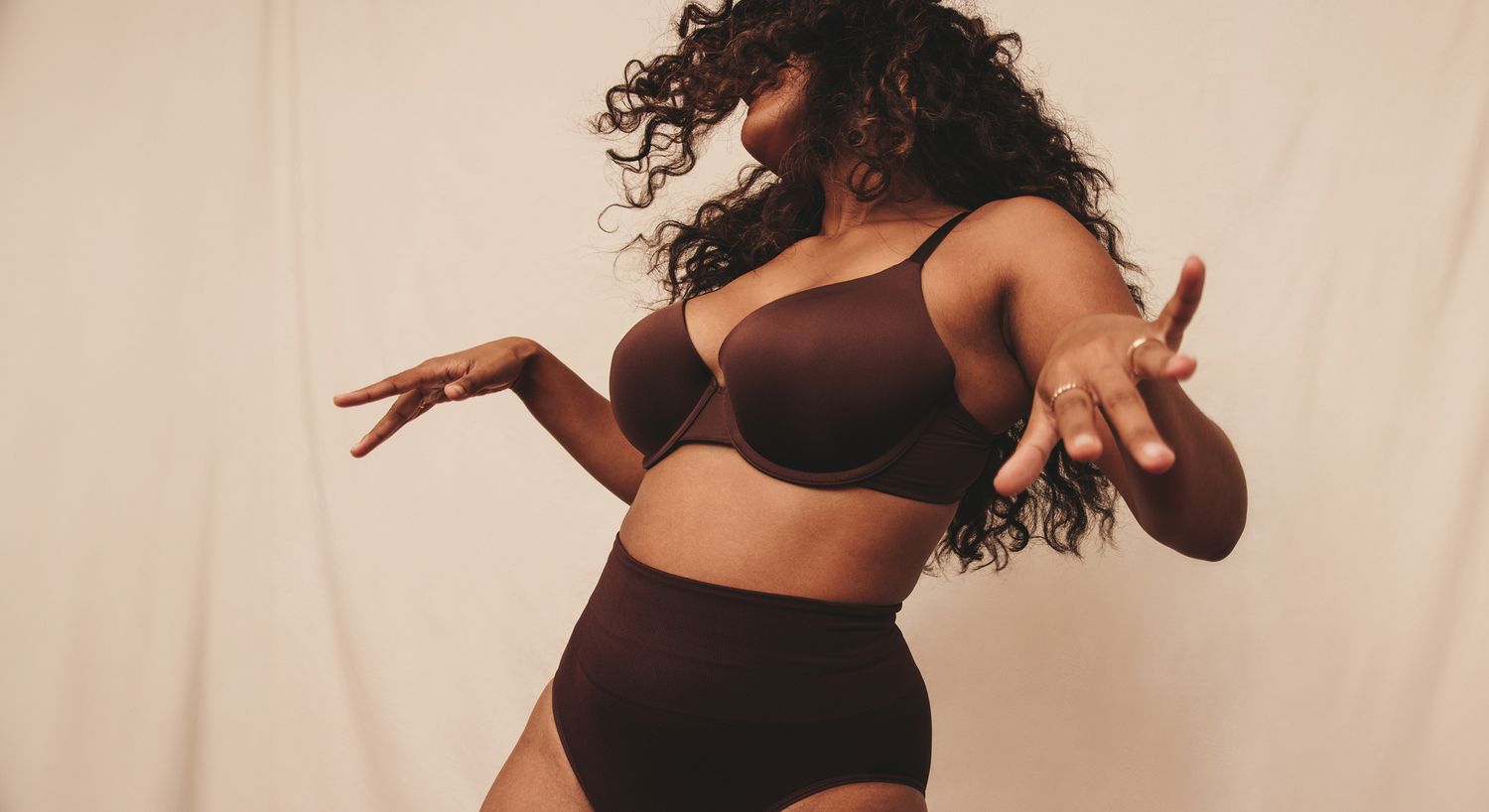 Model in beige outfit against textured background.