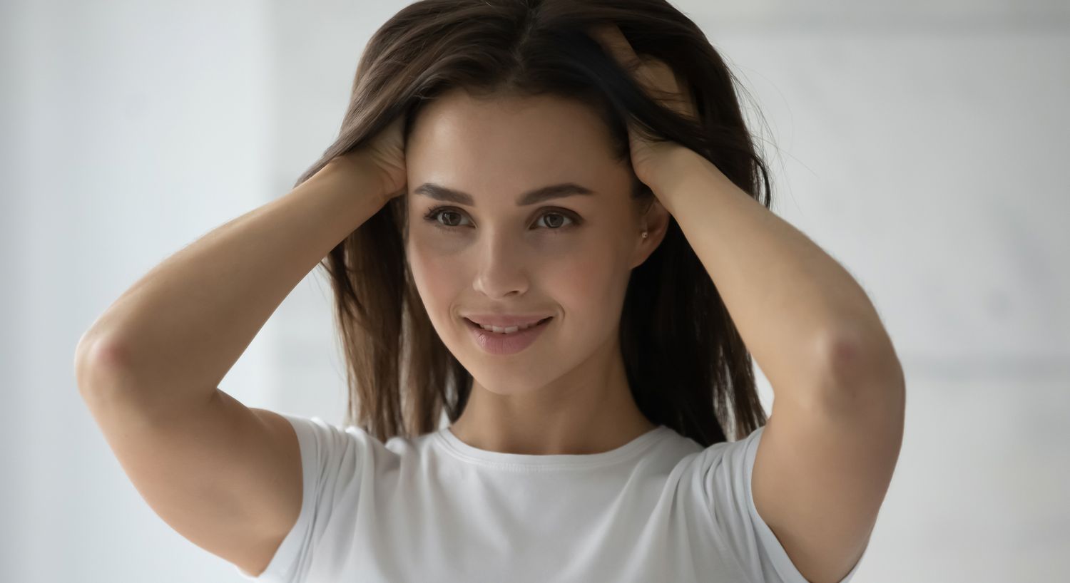Smiling woman with hands in her hair.